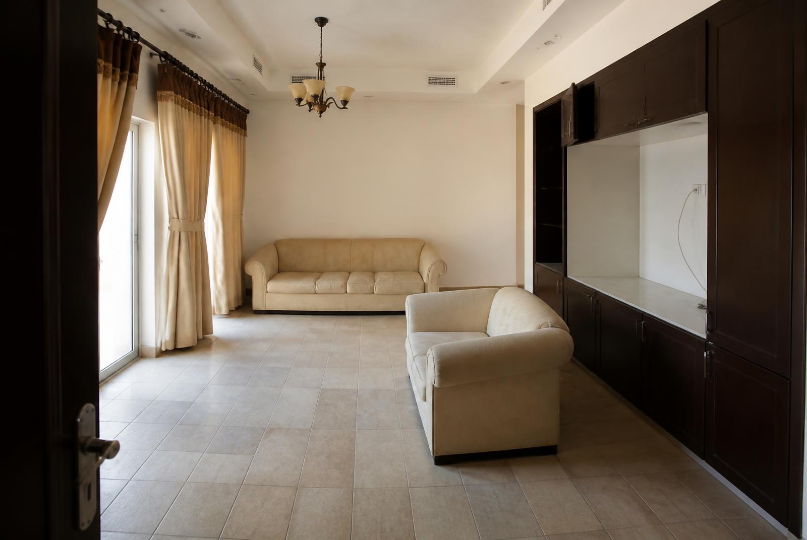 The same living room before renovation, with dated tiling, dark cabinetry and heavy curtains